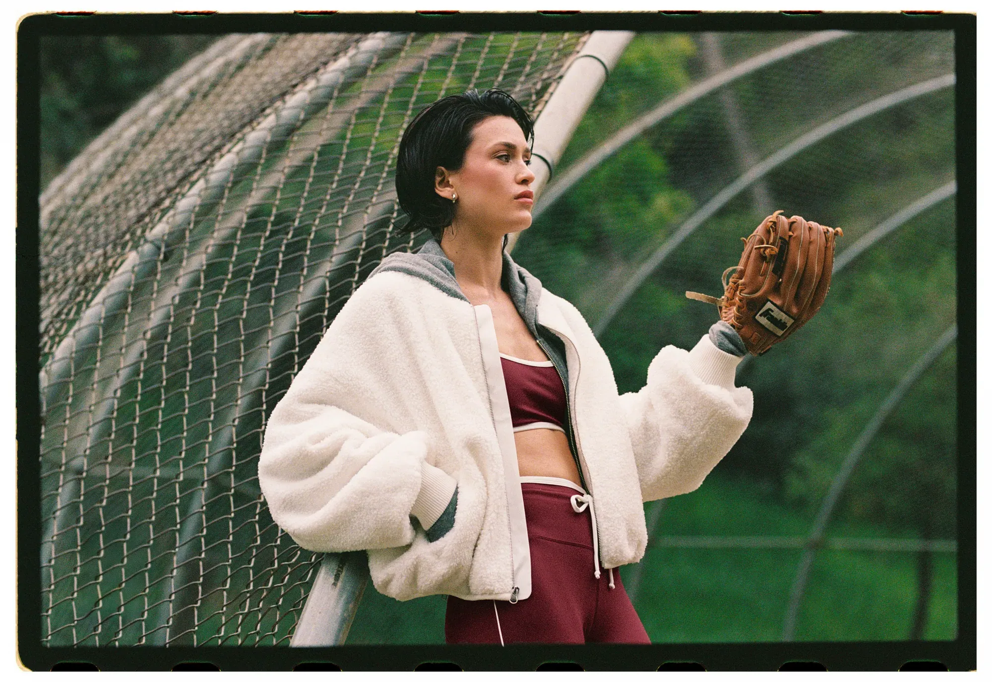 A model against a batting cage in a shearling jacket, film border intact