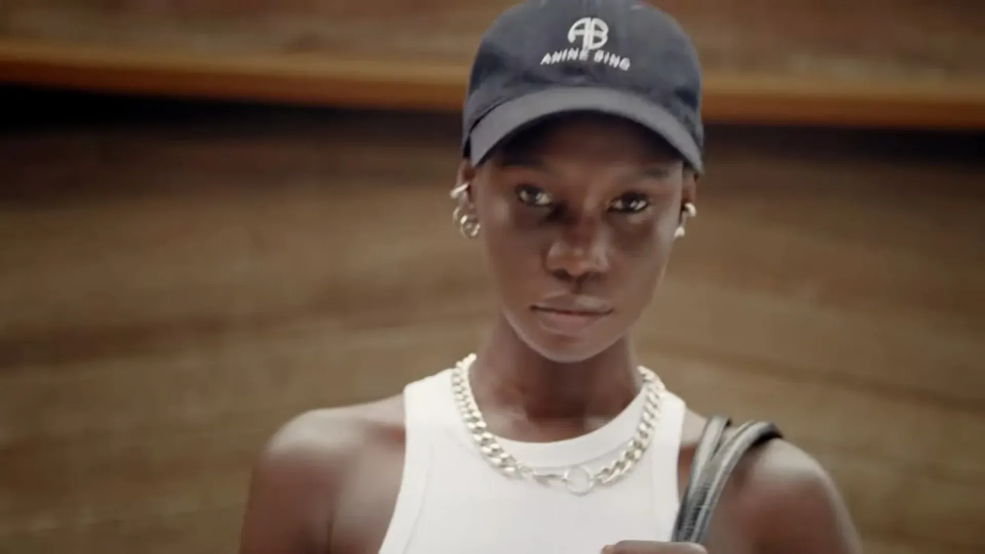 A model in a white tank and cap looking to camera, from the campaign film